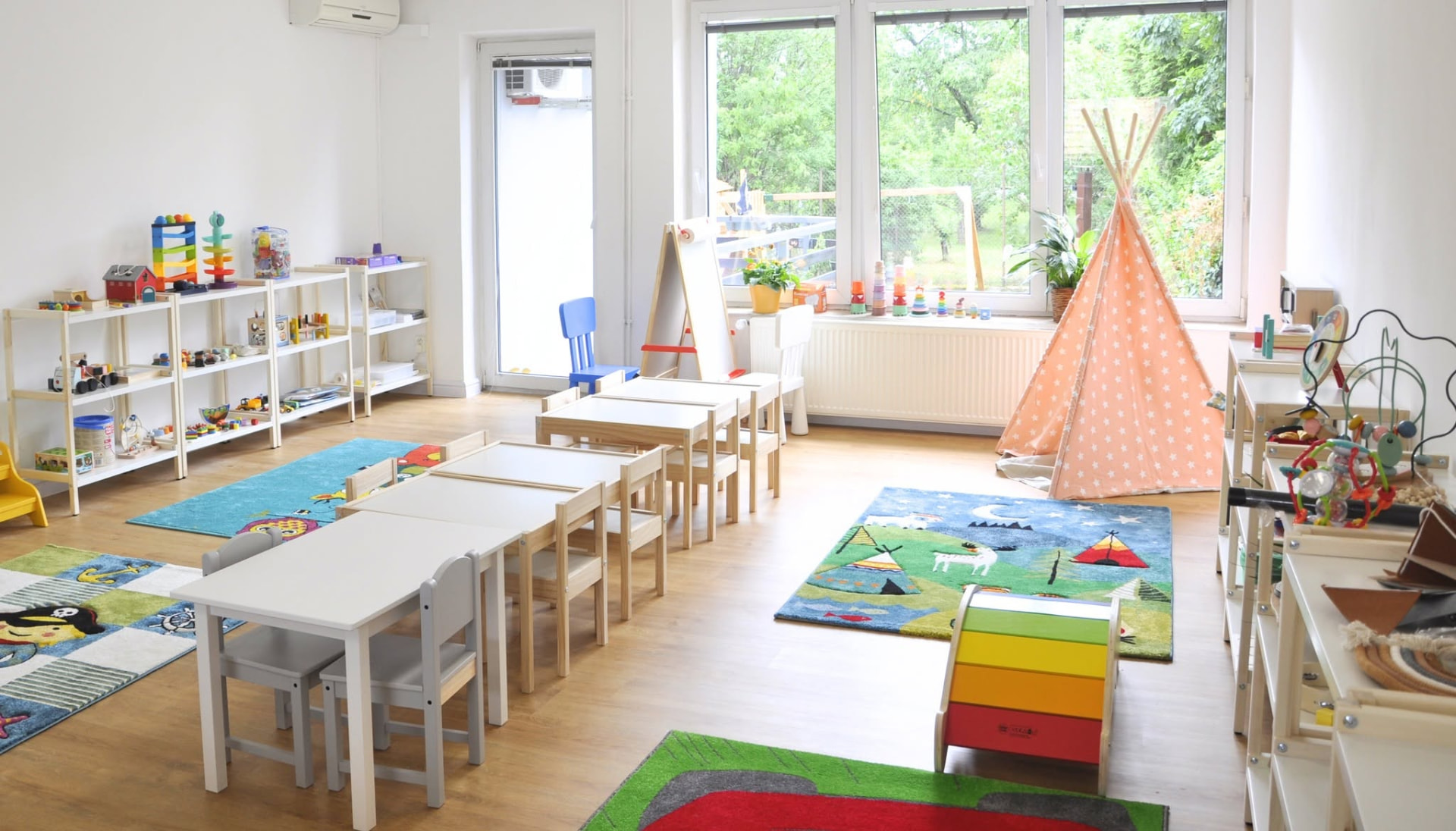 Phòng lớp Montessori của Greenfield với bàn ghế gỗ và góc chơi của các bé